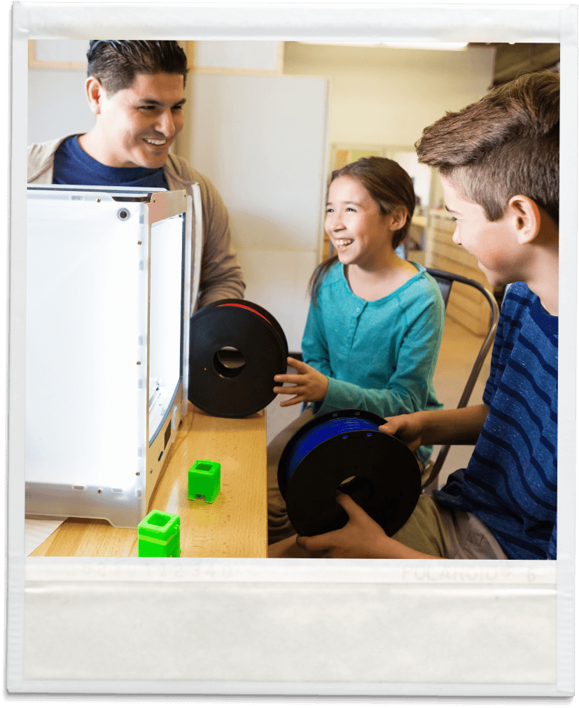 Polaroid mit Schülern und einem Lehrer im Unterricht, welche an einem 3D-Drucker arbeiten. | make & mint - mintLab